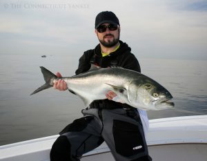 Young man in sunglasses holding large fish on a motorboat