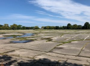 A vast, cracked parking lot with puddles