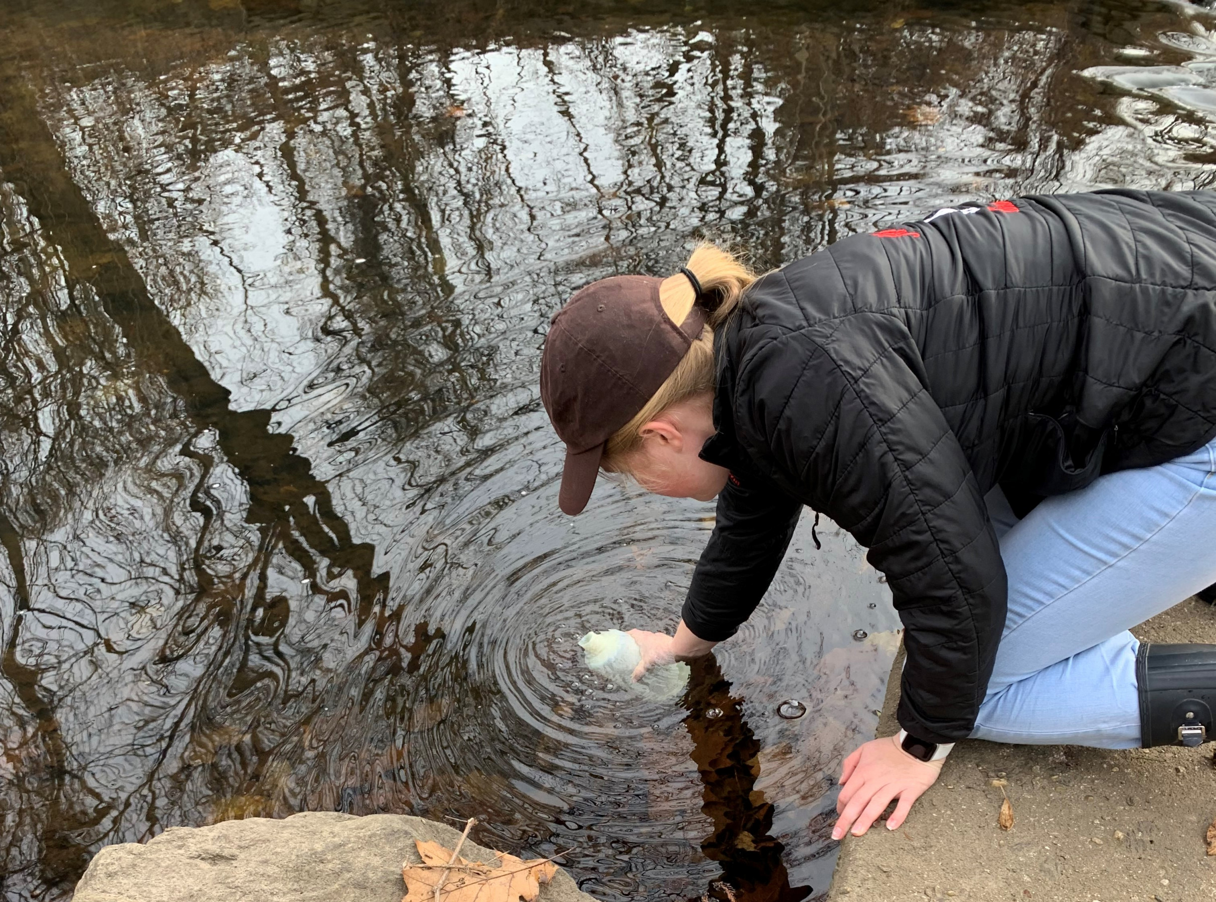 Delia Bajuk, student volunteer at Rye High School, fills water quality sample bottle at Blind Brook Dam.